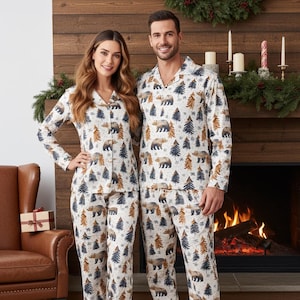 Peut inclure: Ensembles de pyjamas assortis avec un fond crème et un motif répété d'ours bruns et d'arbres bleus et bruns. Le haut à manches longues a une fermeture boutonnée et le pantalon a une taille élastique. Les pyjamas sont en matière douce et confortable.