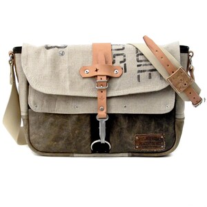 May include: A brown and beige canvas messenger bag with a leather strap and buckle. The bag has a brown leather patch with the text "Peace Love Unity" on it.
