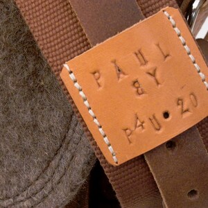 Puede incluir: Una bolsa de cuero marr&oacute;n con una correa de lona marr&oacute;n y un parche de cuero marr&oacute;n que dice "PAUL & BY P4U.20".