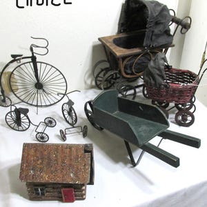 May include: A collection of miniature antique-style toys, including a black metal penny-farthing bicycle, several other bicycles, a green wheelbarrow, a baby carriage, a wicker stroller, and a small wooden house. The word "choice" is written at the top.