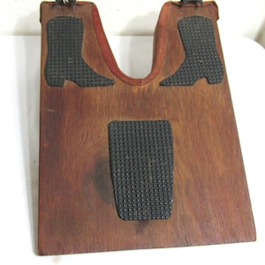 May include: Wooden boot jack with a dark brown finish. Features two black rubber boot-shaped grips and a rectangular footpad. A red suede-like material lines the boot-receiving area. The jack is designed to assist in removing boots.