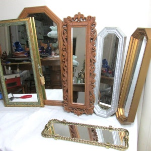 May include: A collection of six antique mirrors with ornate frames. The frames are made of wood and have a variety of finishes, including gold, silver, and brown. The mirrors are all different shapes and sizes.