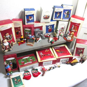 May include: A collection of 20 Hallmark Keepsake Christmas ornaments featuring various themes, including Santa Claus, cats, dogs, and a Harry Potter ornament. The ornaments are displayed on a shelf with their original boxes.