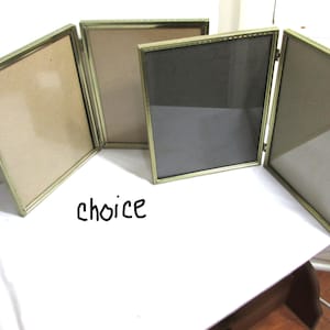 May include: A set of four hinged picture frames with gold-colored metal frames. The frames are open, revealing the backing material. The word "choice" is written in black script at the bottom of the image.
