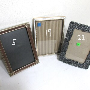 May include: Three decorative picture frames. One frame has a dark brown border with the number 5 in white. Another frame has a gold border with the number 19 in white. The third frame has a gray floral border with the number 22 in white.
