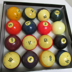 May include: A set of 15 billiard balls in a black case. The balls are numbered 1 through 15 and are in various colors, including yellow, red, blue, green, and brown.