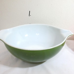 May include: A green and white mixing bowl with a white interior and a green exterior. The bowl has two handles on the sides.