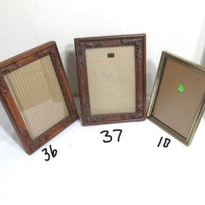 May include: Three vintage picture frames. The frames are in various colors, including brown and gold. The frames have ornate detailing and are empty, ready for photos or artwork. The frames are numbered 36, 37, and 10.