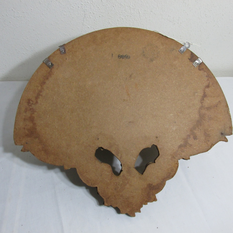 May include: A brown wooden wall shelf with a scalloped edge and intricate carvings. The shelf has two metal brackets on the back for hanging.