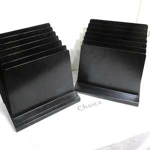 May include: Several stacks of black, rectangular display stands. Each stand has a base and a slightly angled back. The word "Choice" is printed on the white surface.