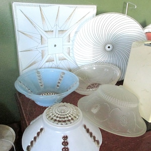 May include: Assortment of vintage glass ceiling light fixtures. The fixtures are in various shapes and sizes, including a square, round, and bowl shape. The fixtures are made of frosted glass and have a white finish.