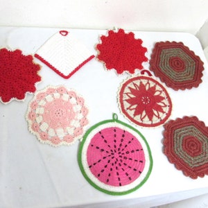 May include: A collection of eight crocheted pot holders in various colors and patterns, including red, pink, white, and green. The pot holders are all circular or square in shape and feature intricate designs.