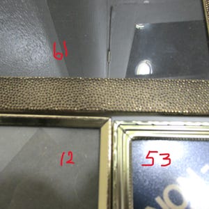 May include: A multi-photo picture frame with a gold-colored beaded border. The frame has multiple openings for displaying photographs. The numbers 61, 12, and 53 are written in red on the frame.