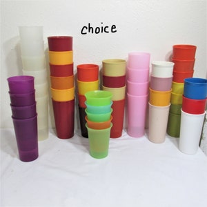 May include: A collection of colorful plastic cups, stacked and arranged in rows. The cups are in various colors, including red, orange, yellow, green, blue, purple, pink, and white. The word "choice" is written in black marker on a white wall behind the cups.