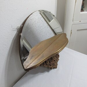 May include: A gold-colored wall shelf with a decorative carved design and a half-round mirror. The shelf is made of wood and has a beveled edge.