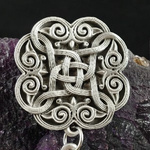 May include: Silver pendant with a detailed Celtic knot design. The pendant is attached to a silver chain.
