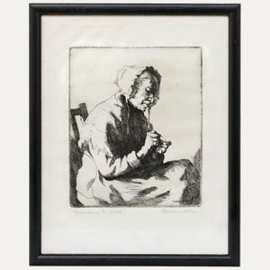 May include: Black and white etching of an elderly person seated, working with their hands. The artwork is framed in a black wooden frame. The title "Threading the needle" is visible at the bottom of the image.