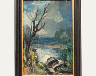 Op de afbeelding: Olieverfschilderij van een waterlandschap met een boot aan de oever. Het kunstwerk heeft een donkere houten lijst met een gouden binnenrand. De schildering toont een bewolkte lucht, een kale boom en een boot aan de oever van een rivier of meer.