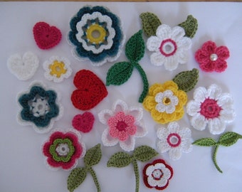May include: A collection of crocheted flowers in various colors, including pink, red, white, yellow, green, and blue. The flowers are arranged on a white background.