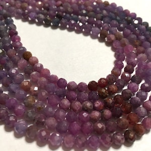 May include: A strand of faceted purple sapphire beads. The beads are a mix of light and dark purple shades.