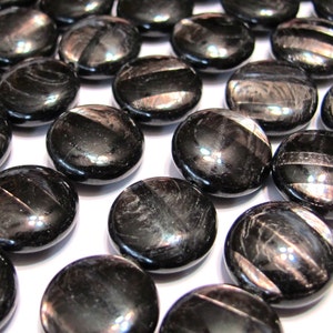 May include: A strand of black obsidian beads with a smooth, round, and flat shape. The beads have a silver sheen and are arranged in a row.
