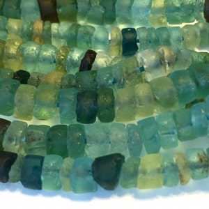 May include: A strand of blue, green, and brown glass beads. The beads are irregular in shape and have a slightly frosted appearance.