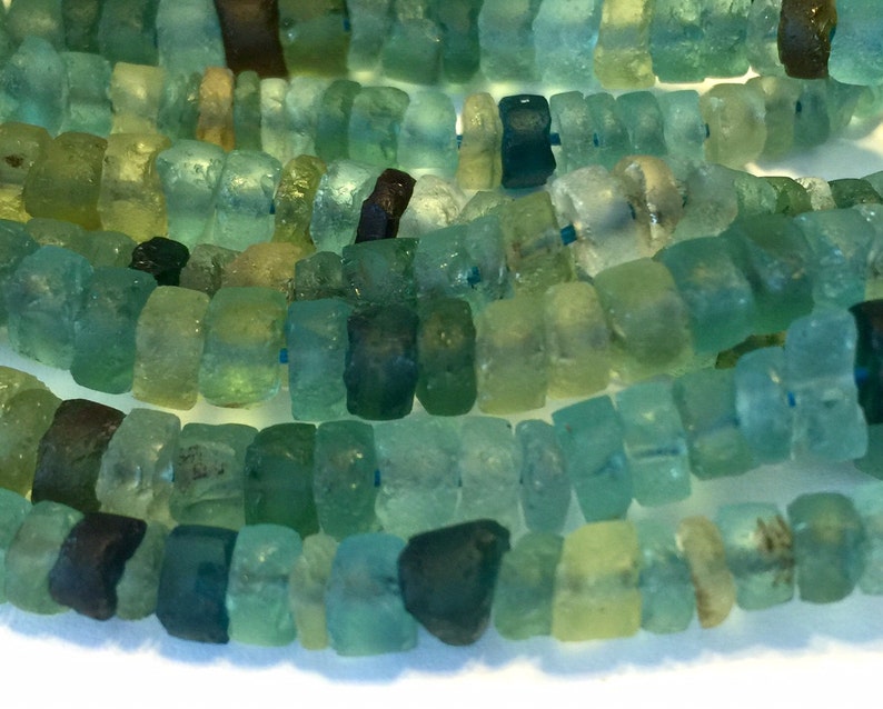 May include: A strand of blue, green, and brown glass beads. The beads are irregular in shape and have a slightly frosted appearance.
