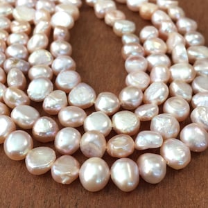 May include: A strand of pink freshwater pearls, with a slightly irregular shape, arranged in a circular pattern. The pearls are smooth and lustrous, with a soft, delicate color.