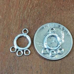 May include: Silver-toned metal connector with a round center loop and three smaller loops on the bottom. The connector is shown next to a US quarter for size comparison.