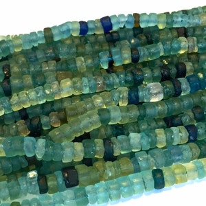 May include: A strand of turquoise, blue, and green glass beads. The beads are irregular in shape and have a rough, textured surface.