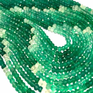 May include: A strand of green gemstone beads, faceted and polished, with a graduated size from small to large. The beads are a light green color, with some having a more translucent appearance.
