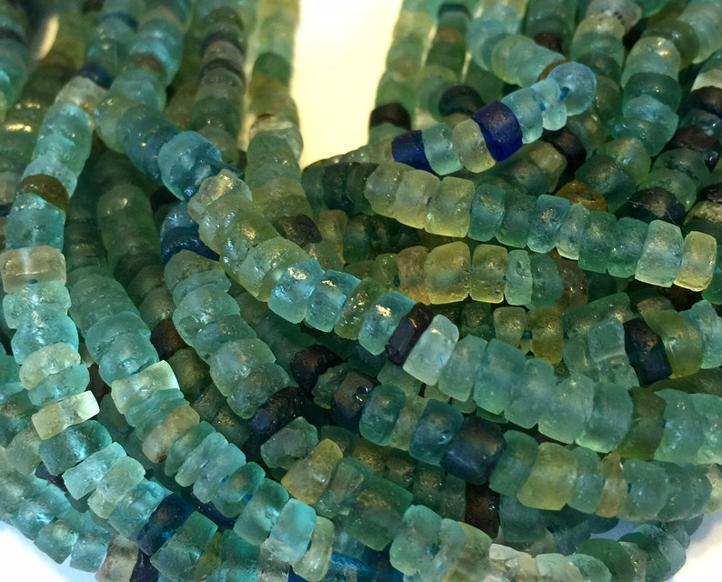 May include: A strand of turquoise, green, and blue glass beads. The beads are square-shaped and have a slightly irregular, handmade look.