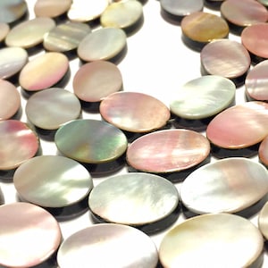 May include: Oval shaped iridescent mother of pearl beads with a black edge. The beads are strung together in a strand.
