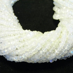 May include: A strand of white moonstone beads, with a slightly iridescent sheen. The beads are small and round, and they are strung together on a clear thread.