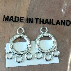May include: Two silver metal jewelry findings with a round loop and four smaller loops. The findings are made in Thailand.