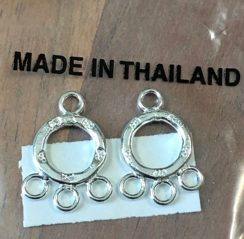 May include: Two silver metal jewelry findings with a round loop and four smaller loops. The findings are made in Thailand.