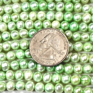 May include: A strand of light green freshwater pearls, with a US quarter for size reference.