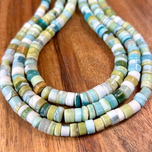May include: A strand of green, blue, and white gemstone beads. The beads are round and have a smooth, polished finish.