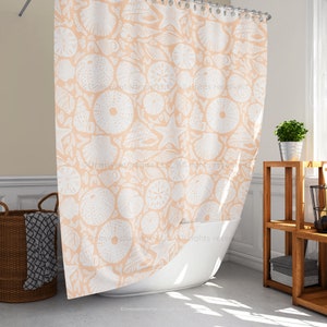 May include: A peach-colored shower curtain with a repeating pattern of white seashells, starfish, and sand dollars. The curtain is hanging in front of a white bathtub. The design creates a coastal or beach theme.