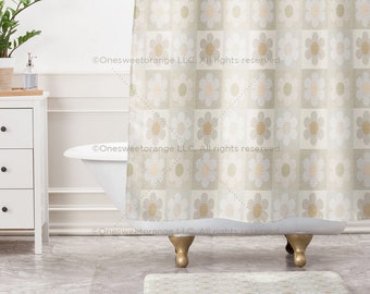 May include: A beige shower curtain with a repeating pattern of white and beige flowers. The shower curtain is hanging in a bathroom with a white bathtub and a white cabinet.