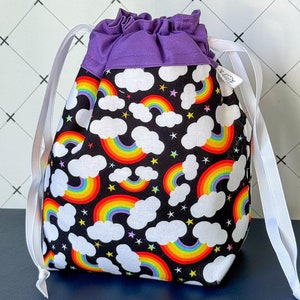 Op de afbeelding: Een paarse trekkoordtas met een zwart-wit regenboogprint. De tas heeft een wit trekkoord en een paarse voering.