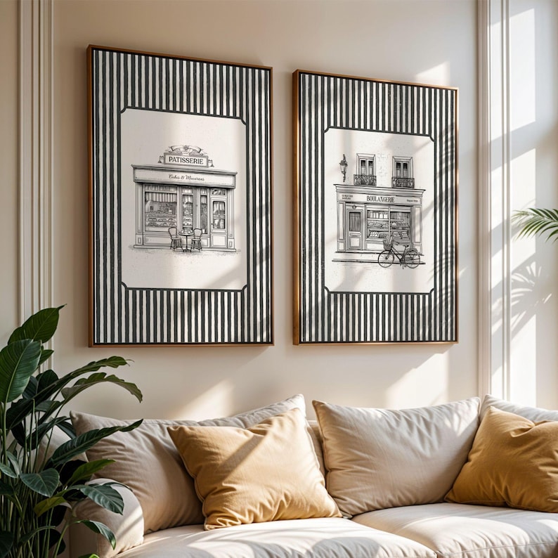 May include: Two framed art prints depicting French bakery storefronts. Each print features a black and white illustration set against a striped background. One print reads "Patisserie" above the bakery. The other print shows a bicycle.