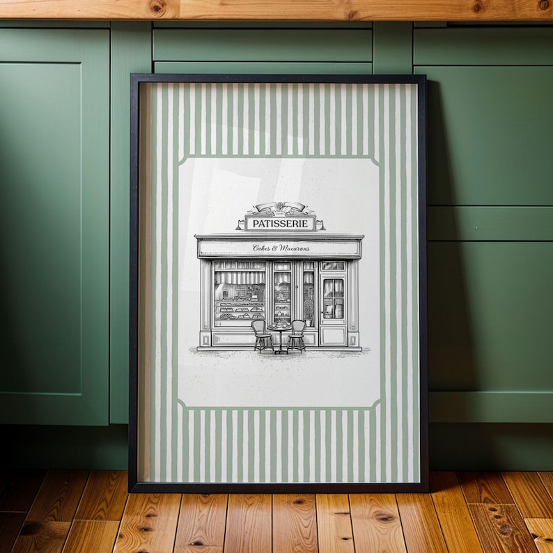 May include: Framed black and white illustration of a French patisserie. The artwork features a detailed drawing of a bakery storefront with the word "Patisserie" above the entrance. The background has a green and white striped pattern.
