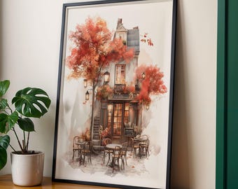 May include: Framed watercolor print of a quaint cafe scene. The artwork features a building with a detailed facade, surrounded by tables and chairs. Autumnal trees with red and orange leaves frame the building. The print is in a black frame.