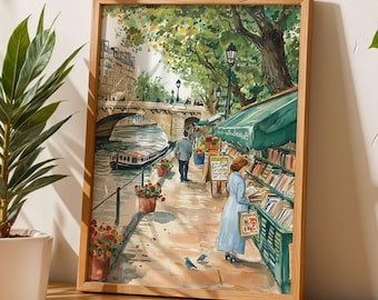 May include: A watercolor painting of a Parisian street scene with a bridge over a canal, a bookstore with a green awning, and people walking by. The painting is framed in a light wood frame.