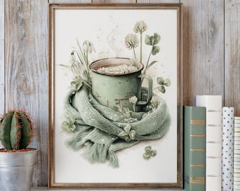 May include: A framed print featuring a green enamel mug filled with tea and flowers, wrapped in a green scarf. The artwork includes shamrocks and snowdrop flowers, evoking a cozy, springtime theme. The frame is a warm brown color.
