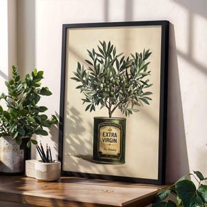 Puede incluir: L&aacute;mina bot&aacute;nica enmarcada que presenta un olivo que crece de una lata de aceite de oliva vintage. La obra de arte muestra ramas y aceitunas verdes sobre un fondo crema. La lata est&aacute; etiquetada como "EXTRA VIRGIN" en letras doradas, con un marco negro.