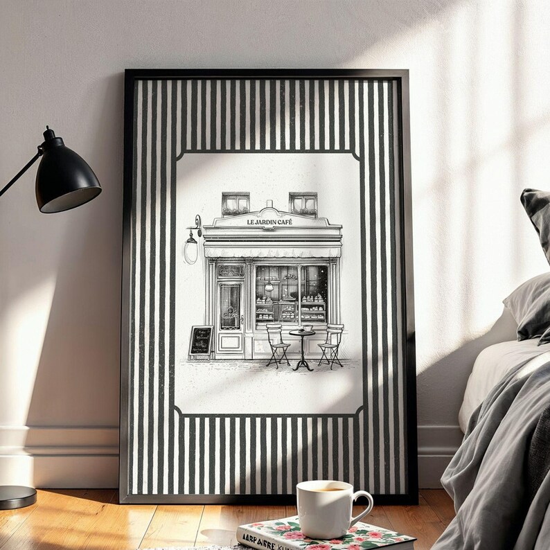 May include: Black and white framed print of a cafe scene. The artwork features a detailed illustration of a cafe with outdoor seating, a sign, and the text "LE JARDIN CAFE". The frame has a black and white striped border.