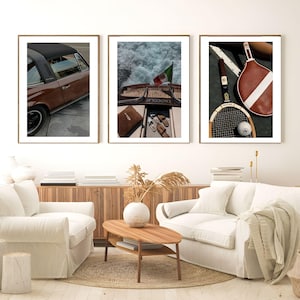 May include: Three framed art prints. The left print shows a brown car with a black roof. The centre print depicts a boat with an Italian flag. The right print displays a tennis racket, ball, and paddle.