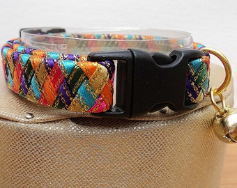 May include: A colorful braided cat collar with a black plastic buckle and a gold bell. The collar is made of woven ribbons in shades of pink, orange, green, blue, purple, and gold.